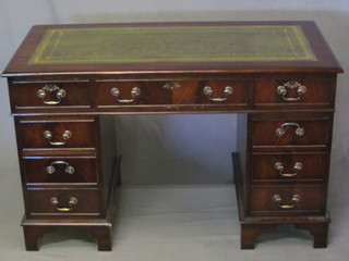 A Georgian style mahogany kneehole pedestal desk with green inset writing surface above 1 long and 8 short drawers 48"