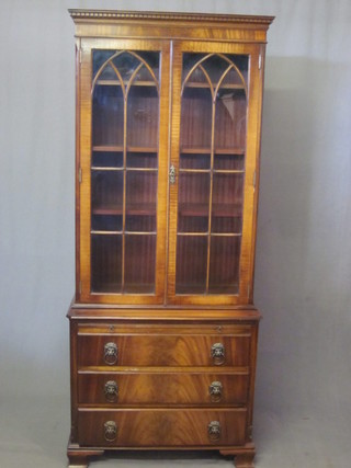 A Georgian style mahogany display cabinet on chest, the upper section with moulded and dentil cornice, the shelved interior  enclosed by astragal glazed panelled doors, the base fitted a  brushing slide above 3 long drawers with lion mask handles,  raised on ogee bracket feet 29"