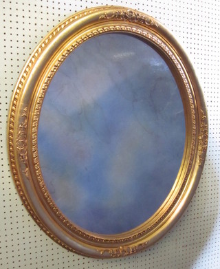 An oval plate wall mirror contained in a gilt frame 37"