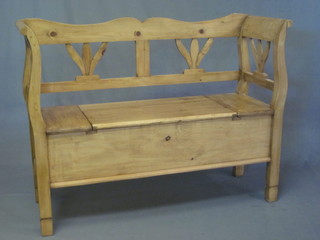 A stripped and polished pine settle with pierced back, the seat  with hinged lid 48"