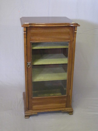 An Edwardian walnut music cabinet enclosed by a glazed  panelled door and raised on ogee bracket feet 19"