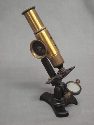 A student's brass single pillar microscope contained in a wooden carrying case
