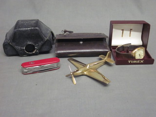 An Olympus 35RD camera, a Timex wristwatch, a brass model  of a spitfire, a Swiss Army knife and a wallet