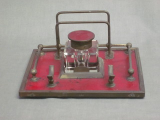 A square glass inkwell, raised on a red enamelled and gilt metal stand 8"
