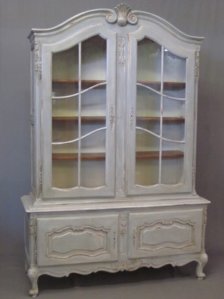 A French blue painted cabinet on cabinet with arched top, the interior fitted shelves enclosed by astragal glazed panelled doors,  the base fitted a double cupboard, raised on cabriole supports 51"