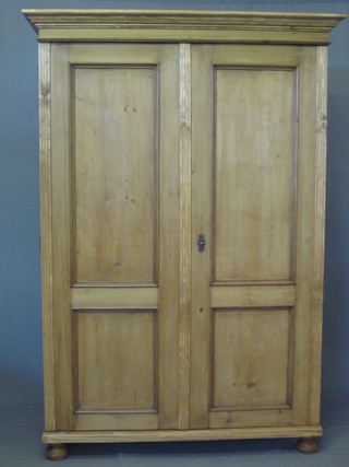 A Continental stripped and polished pine cupboard with moulded cornice, the interior fitted adjustable shelves enclosed by panelled  doors, raised on bun feet 52"