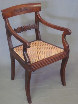 A 19th Century Colonial mahogany bar back open arm desk chair  with carved mid rail and woven cane seat, raised on sabre  supports