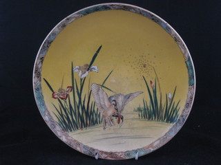 An Oriental yellow glazed dish decorated a diving bird amidst reeds 10"
