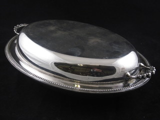 A silver plated twin handled entree dish with bead work border