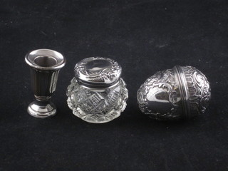 A 19th Century embossed Continental white metal egg shaped  trinket box with hinged lid and gilt metal interior, a circular cut  glass rouge pot with silver mount and a white metal taper stick