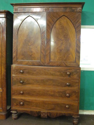 A Victorian mahogany linen press with moulded cornice, the  interior fitted 2 shallow shelves enclosed by a pair of arch  panelled doors, the base fitted 4 long drawers with tore handles,  raised on turned supports ending in bun feet 55"