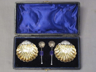 A pair of Victorian silver scallop shaped salts and spoons, Birmingham 1876, 1 oz, cased