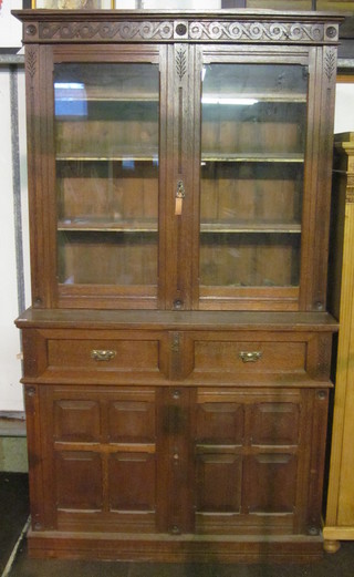 A Victorian Art Nouveau oak secretaire bookcase, the upper  section with carved and moulded cornice the interior fitted  shelves enclosed by glazed panelled doors, the base fitted a  secretaire drawer above a double cupboard, raised on a platform  base 50"