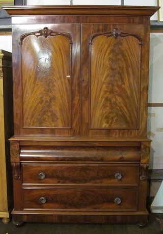 A Victorian mahogany linen press with moulded cornice, the  interior fitted 2 shallow shelves enclosed by panelled doors, the  base fitted a secret drawer above 2 long drawers and with  vitruvian scrolls to the sides, raised on bun feet 53"