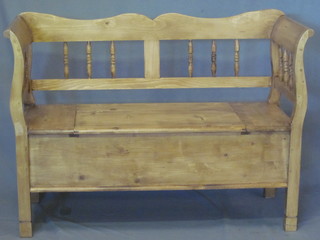 A Continental stripped and polished pine settle with bobbin  turned decoration, the seat with hinged lid 49"