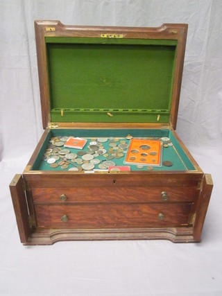 An oak canteen box containing a collection of coins