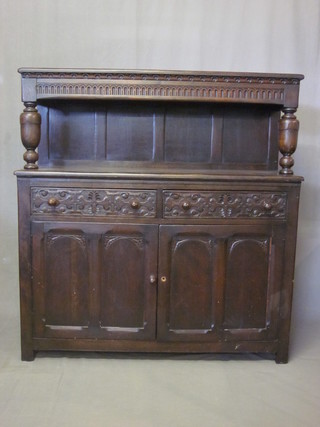 A carved oak court cupboard with raised back, the base fitted 2 drawers above a double cupboard 49"
