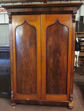 A William IV mahogany wardrobe with moulded cornice  enclosed by panelled doors, raised on bun feet 59"