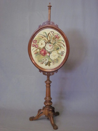 A Victorian bleached mahogany pole screen with oval woolwork banner with floral decoration, raised on a fluted tripod base