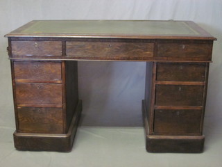 An oak kneehole pedestal desk with green inset tooled leather  writing surface, fitted 1 long and 8 short drawers 48"