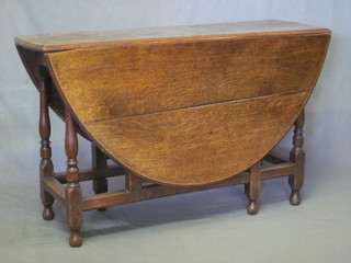 A honey oak oval drop flap gateleg dining table raised on turned supports 47"