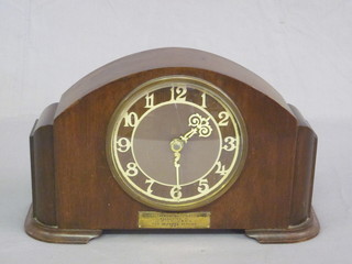An Art Deco mantel clock with Arabic numerals contained in an  arch shaped mahogany case