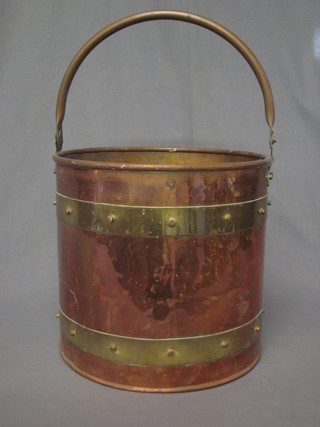 A circular copper and brass coal bucket with swing handle