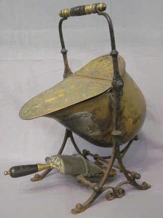 A Victorian embossed brass coal scuttle raised on a wrought iron stand