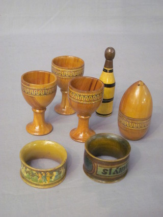 3 treen egg cups, 2 treen napkin rings, a trinket box in the form of a bottle of Champagne and 1 other trinket box