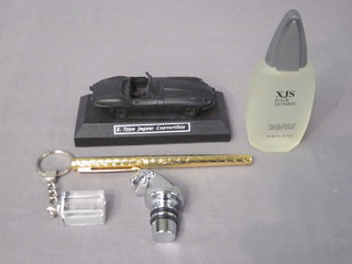 A Jaguar fountain pen, a bottle of XJS aftershave, a chrome Jaguar bottle stopper, a glass Jaguar key ring and a model of an  convertible E Type Jaguar