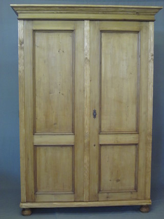 A Continental stripped and polished pine cupboard with moulded cornice, the interior fitted adjustable shelves enclosed by panelled  doors, raised on bun feet 52"