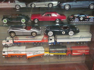 A wooden display cabinet containing 8 model cars and 5  articulated lorries