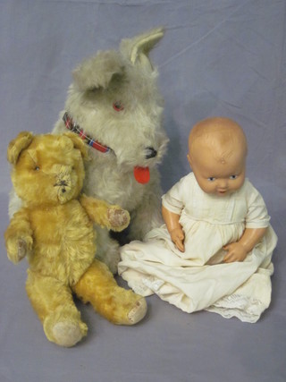 A cuddly figure of a seated dog, a yellow teddybear and a doll
