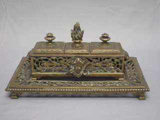 A 19th Century rectangular pierced brass inkwell having a stamp  box to the centre, flanked by a pair of inkwells, raised on  panelled feet 11", glass wells missing,