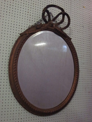A 19th Century oval plate wall mirror contained in a decorative  gilt frame surmounted by a ribbon garland, f, 36"