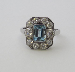A lady's 18ct white gold dress ring set a rectangular cut aquamarine surrounded by diamonds, approx 1.25/1.40ct