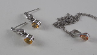 A white gold necklace set a diamond and orange sapphire  together with a pair of matching earrings