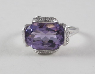 A 14ct white gold dress ring set an oval cut amethyst surrounded  by diamonds