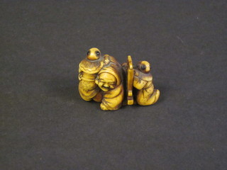A carved ivory Netsuke in the form of a kneeling man with attendants 1"