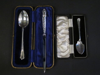 A silver preserve spoon cased, a silver handled paper knife and a silver plated spoon cased