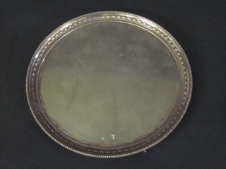A circular silver plated salver raised on 3 ball and claw feet 10"