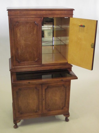 A Georgian style walnut cocktail cabinet with moulded cornice,  the upper section enclosed by a panelled door, the base with  brushing slide above 1 long drawer enclosed by a panelled door,  raised on bracket feet 28"