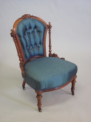 A Victorian walnut showframe nursing chair upholstered in blue material, raised on turned and fluted supports