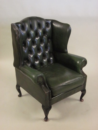 A Georgian style mahogany wing armchair upholstered in green button back leather