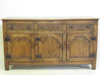 An oak dresser base fitted 3 long drawers above triple cupboards with arcaded decoration 66"