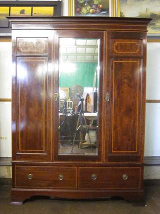 An Edwardian inlaid mahogany triple wardrobe with moulded  cornice enclosed by a bevelled plate mirror panelled door, the  base fitted 2 long drawers, raised on bracket feet, by Maples 66"