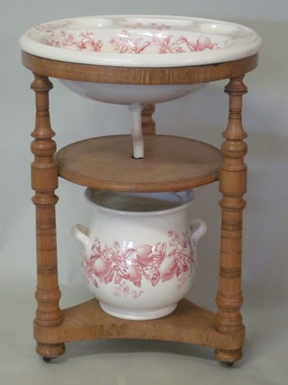 A Victorian circular oak wash stand, raised on a turned column  with triform base, complete with porcelain basin  ILLUSTRATED