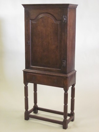 A 17th Century style oak side cabinet with moulded cornice, enclosed by an arched panelled door, the base fitted 1 long  drawer, raised on turned and block supports 27"