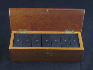 A mahogany box with wooden lid containing ebony and bone  dominoes