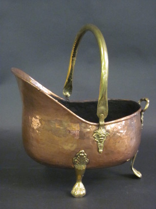 A copper helmet shaped coal scuttle raised on brass feet